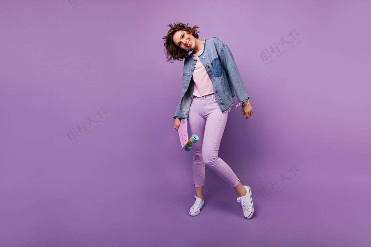 美丽穿着紫色裤子的迷人的欧洲模特的全长照片漂亮的高加索女孩剪短发摆姿势的室内照片女人舞蹈幸福