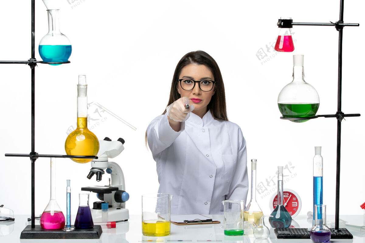 科学前视图穿着白色医疗服的女化学家正坐在白色背景上写着解决方案科学大流行实验室病毒冠状病毒办公室病毒专业