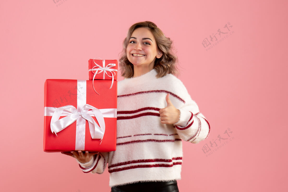 成人正面图年轻女性手持圣诞礼物粉色圣诞节肖像
