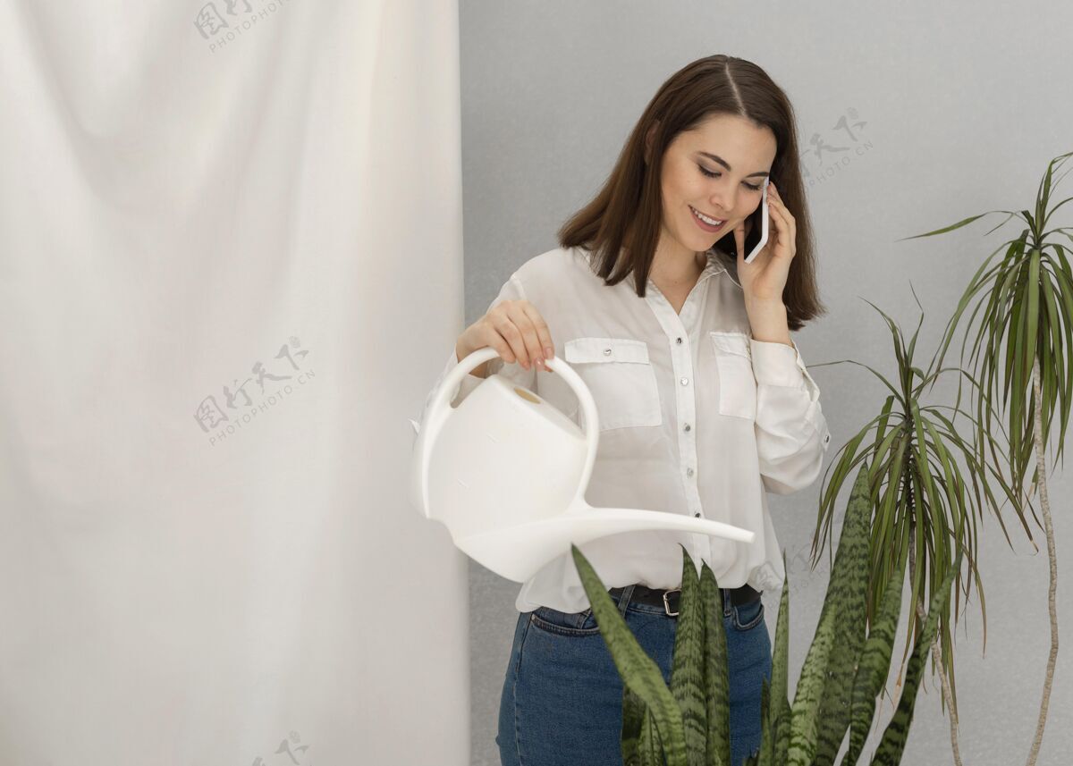排毒肖像女子一边浇灌植物一边讲手机水壶女人移动