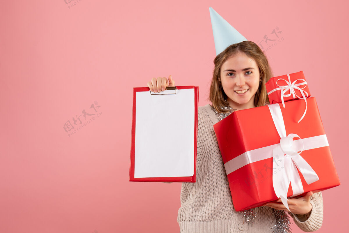 礼物正面图年轻女性手持圣诞礼物和纸条圣诞节笔记微笑