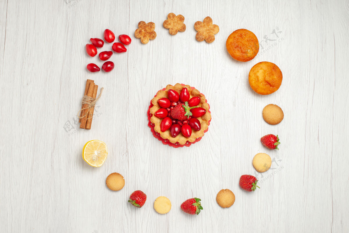 框架在白色的桌子上俯瞰带有水果和蛋糕的小饼干水果形状花