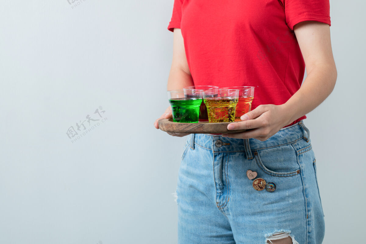聪明穿着红衬衫的年轻女孩手里拿着一盘五颜六色的饮料人体模特鸡尾酒酒保
