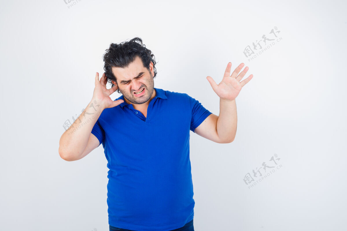 老年人成熟的男人用手指堵住耳朵 穿着蓝色t恤展示停止的手势 看起来很恼火前视图表情成熟老年人