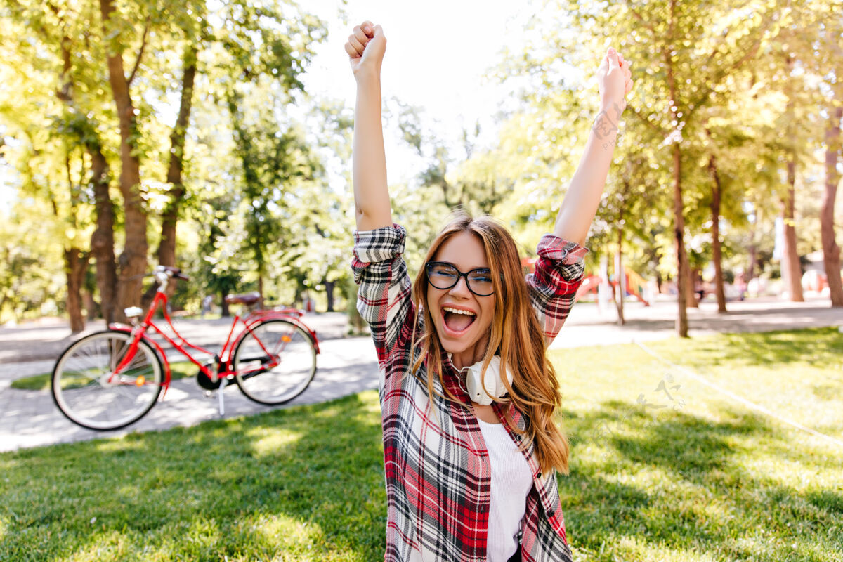 自行车可爱的年轻女子在公园里表达激动的情绪高兴的欧洲女孩在户外穿格子衬衫美丽行动微笑
