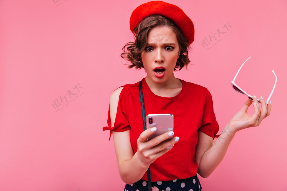 手机心烦意乱的短发女孩读着电话留言惊讶的法国女模特戴着贝雷帽张嘴摆姿势的室内照片表情年轻手机