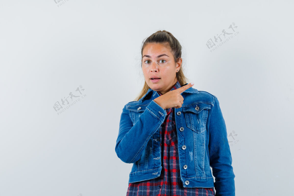 女人穿着衬衫 夹克衫的年轻女子站在一边 看上去很自信 正对着前方脸手指向