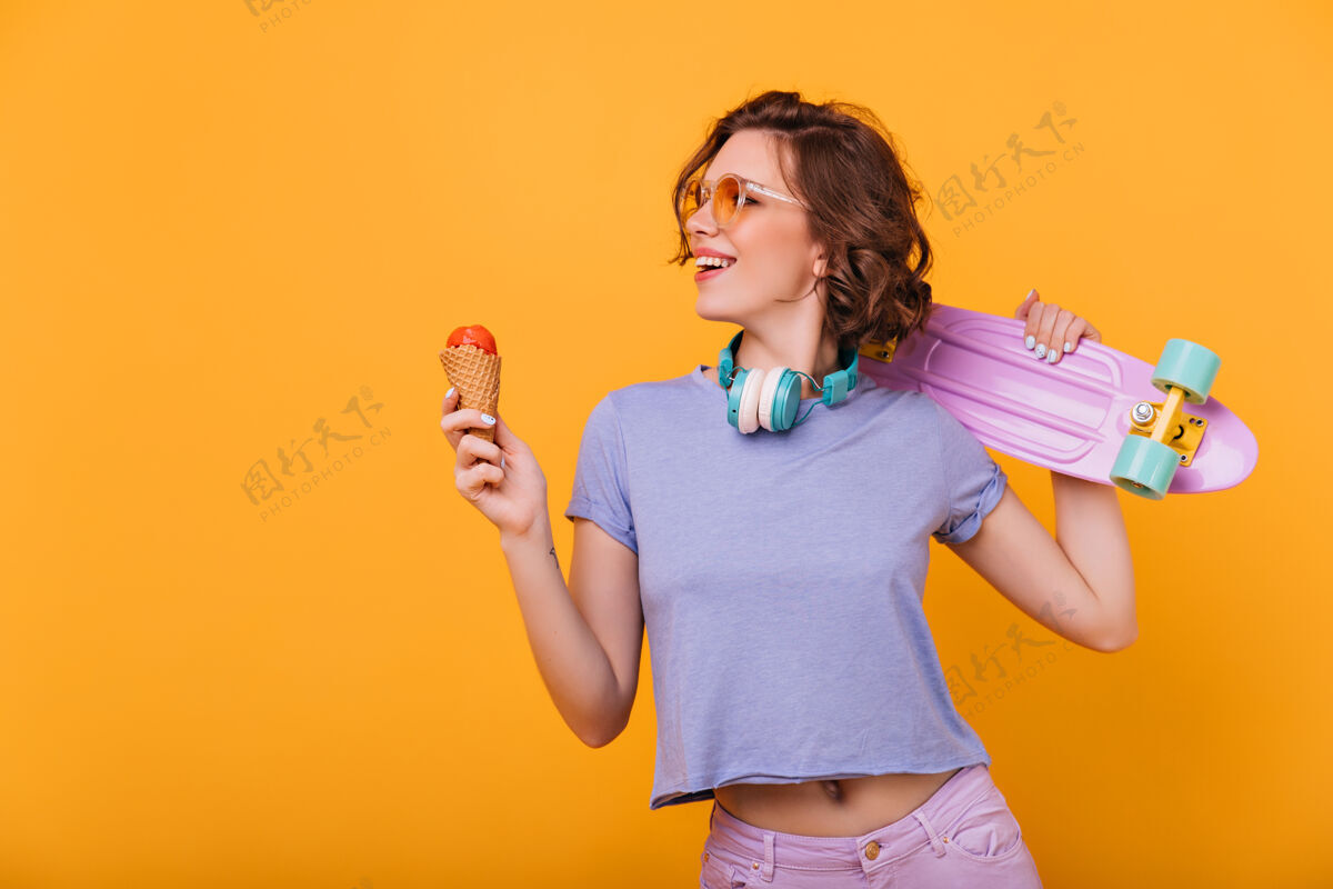 明亮苗条的欧洲女士 带着美味的冰淇淋微笑热情的女模特 带着滑板 享受着最喜欢的甜点模特爱好运动