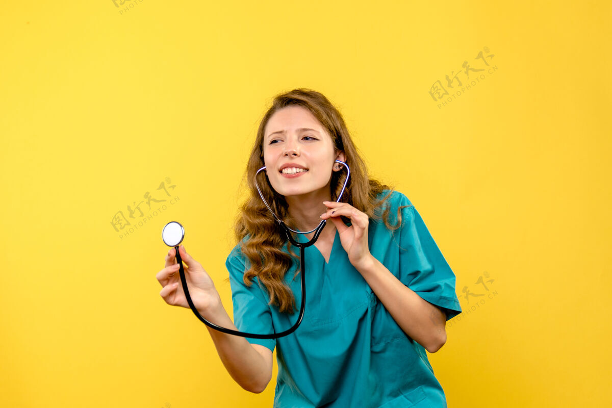 女医生黄色墙上女医生使用听诊器的正面图保健仪器成人