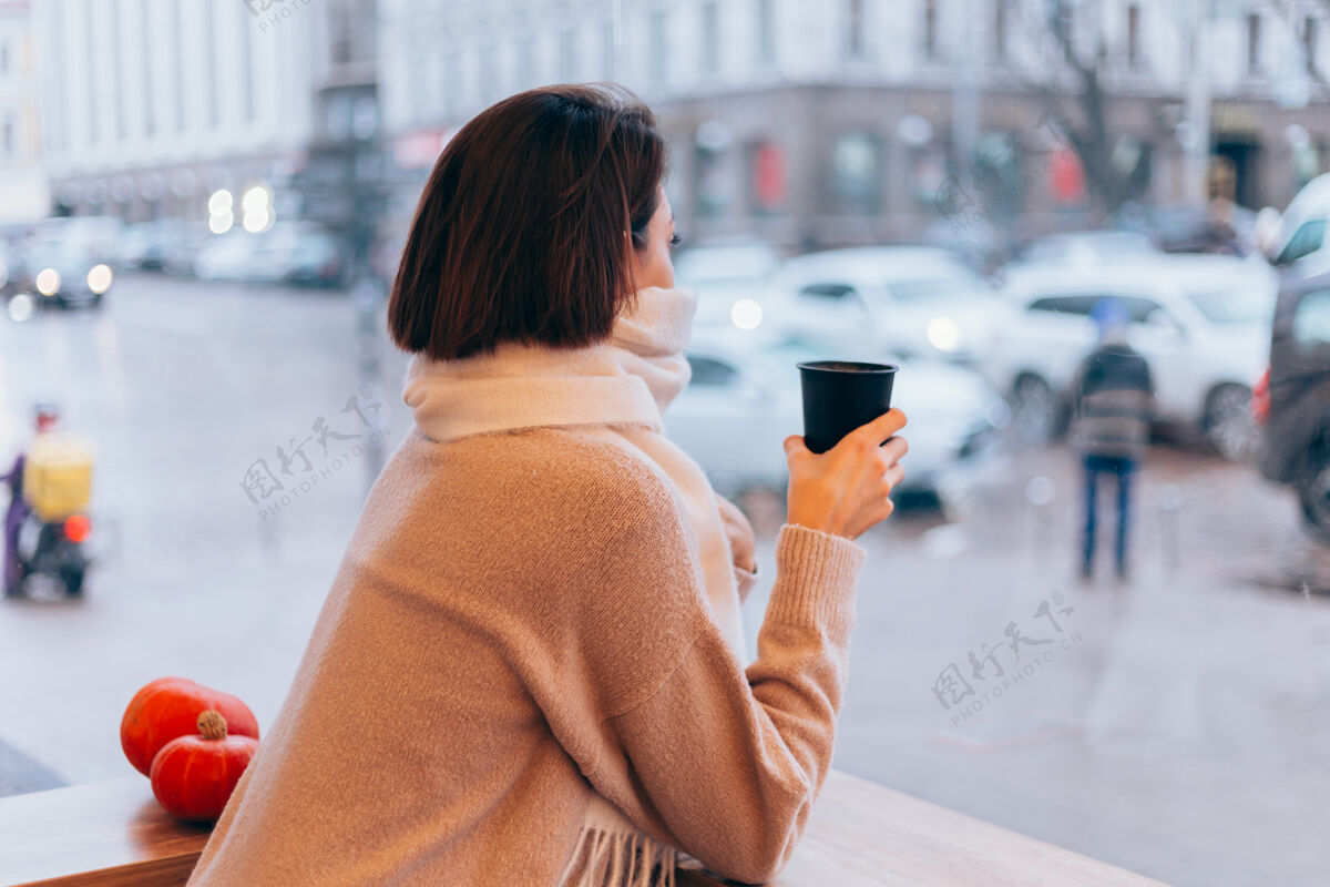 时尚一个女孩在舒适的咖啡馆里用一杯热咖啡取暖冷咖啡店脸