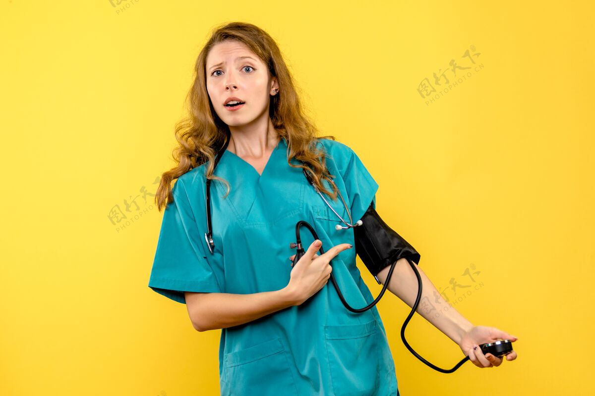 护理女医生在黄色墙壁上测量压力的正面图医疗器械专业制服