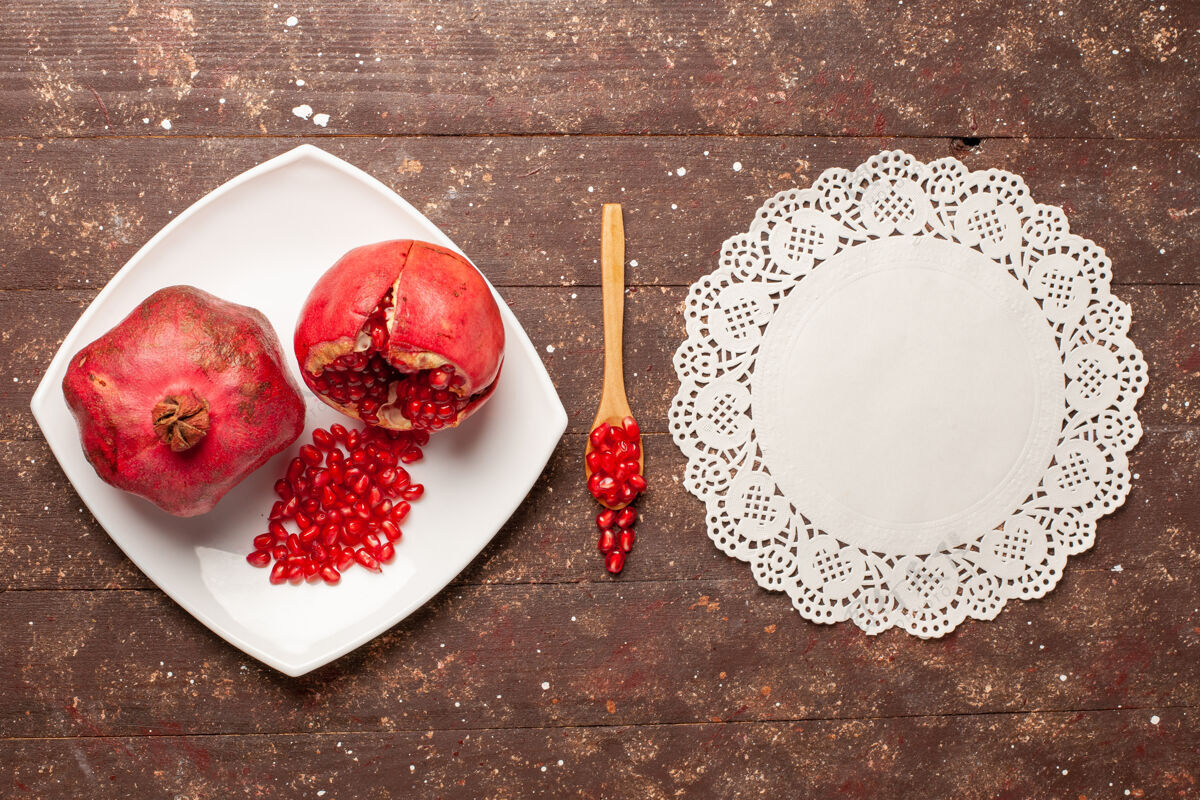 桌子在棕色乡村书桌上的盘子里俯瞰新鲜的红色石榴浆果糖果顶部