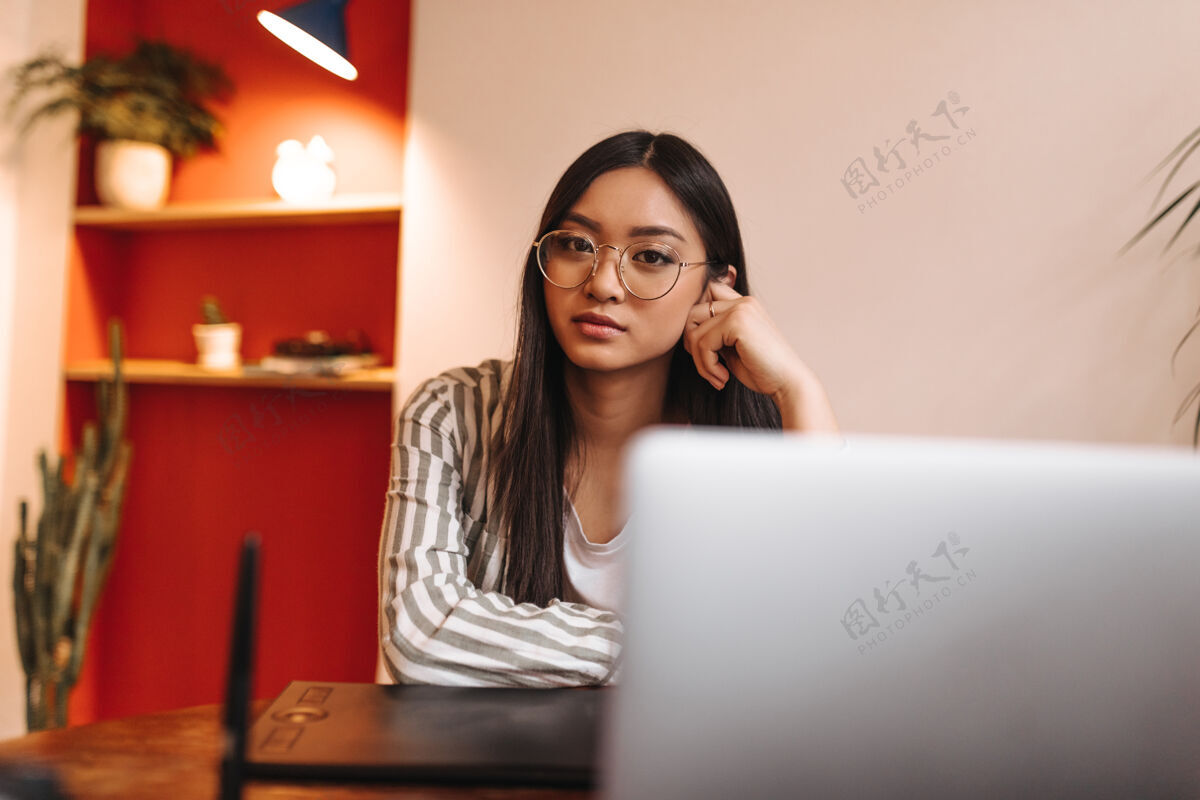 商务穿着条纹夹克 戴眼镜的女商人正靠在桌上 靠着笔记本电脑看前面坐着计算机办公室