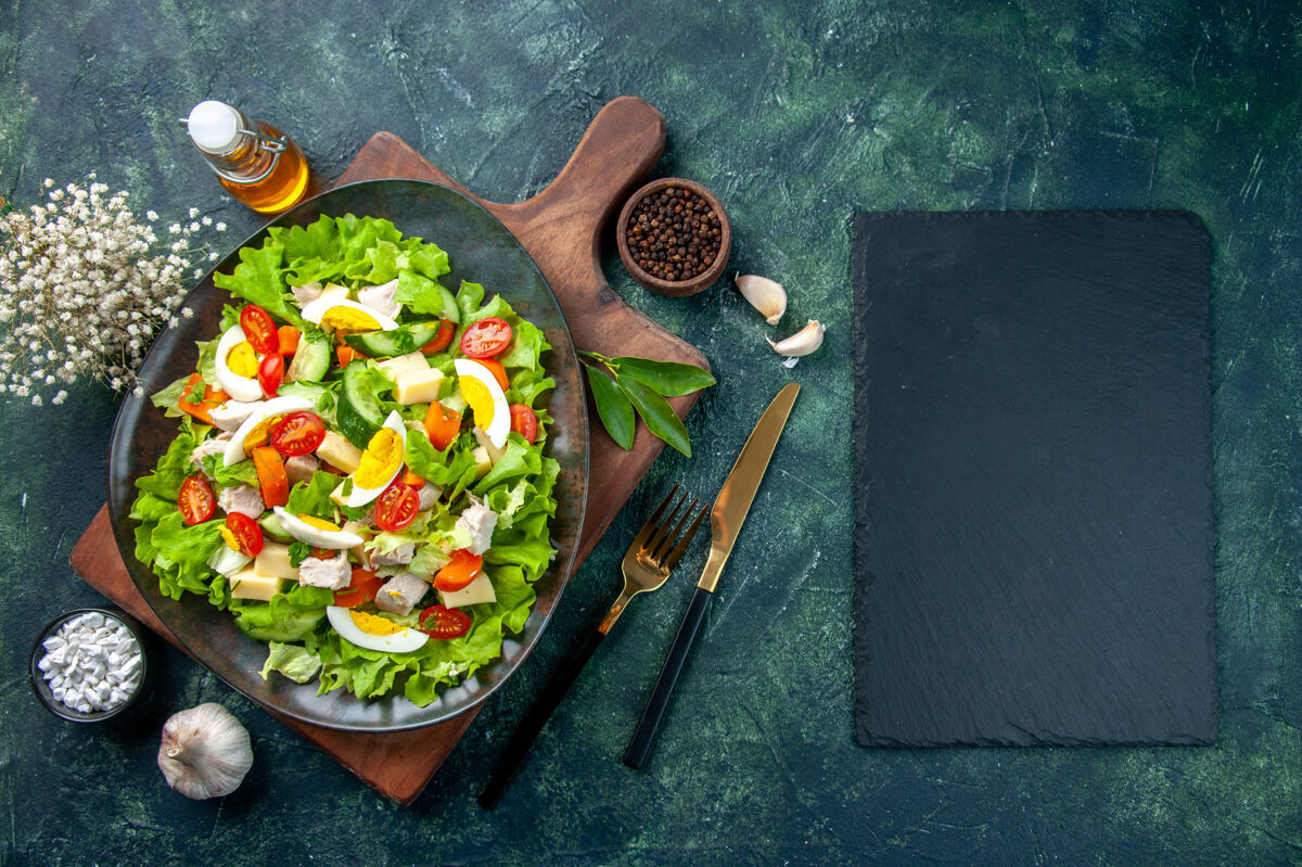 混合俯瞰美味的沙拉与新鲜的原料在木制砧板香料油瓶大蒜素餐具集黑色混合色背景餐具午餐餐盘