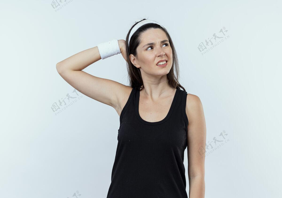 失误戴着头巾的年轻健身女 手放在头上 站在白色背景上 看向一边 因为她犯了错误站立手年轻