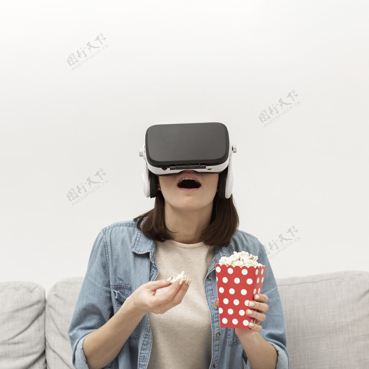 虚拟现实耳机戴着虚拟现实耳机的女性肖像？吃爆米花女人爆米花设备