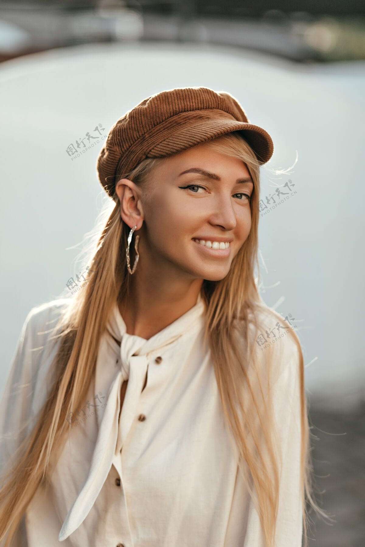模型快乐迷人的女人穿着时髦的棉质衬衫 戴着时髦的棕色帽子 笑容满面 心情愉快地走在外面人成人人