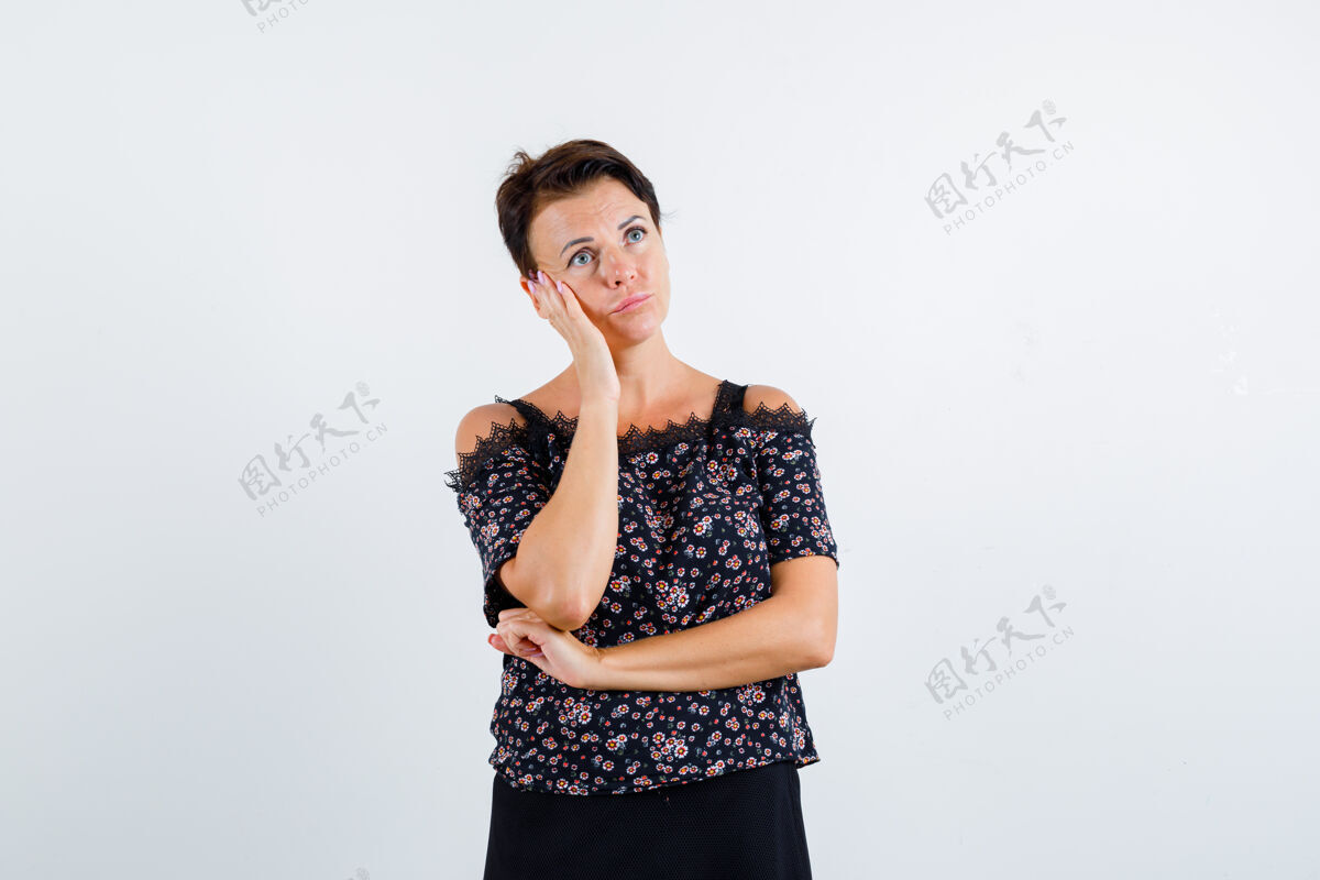 前面一个穿着花衬衫的成熟女人 黑色的裙子 面颊靠在手掌上 想着什么 神情沉思 俯瞰前方优雅女人老年人