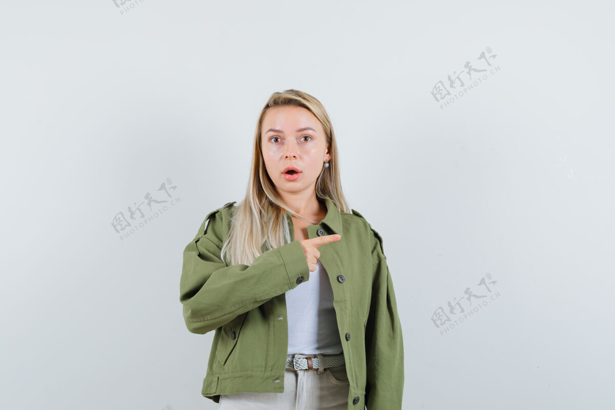 单身穿着夹克衫的年轻女士指着右边 一脸惊讶正视图健康夹克女孩