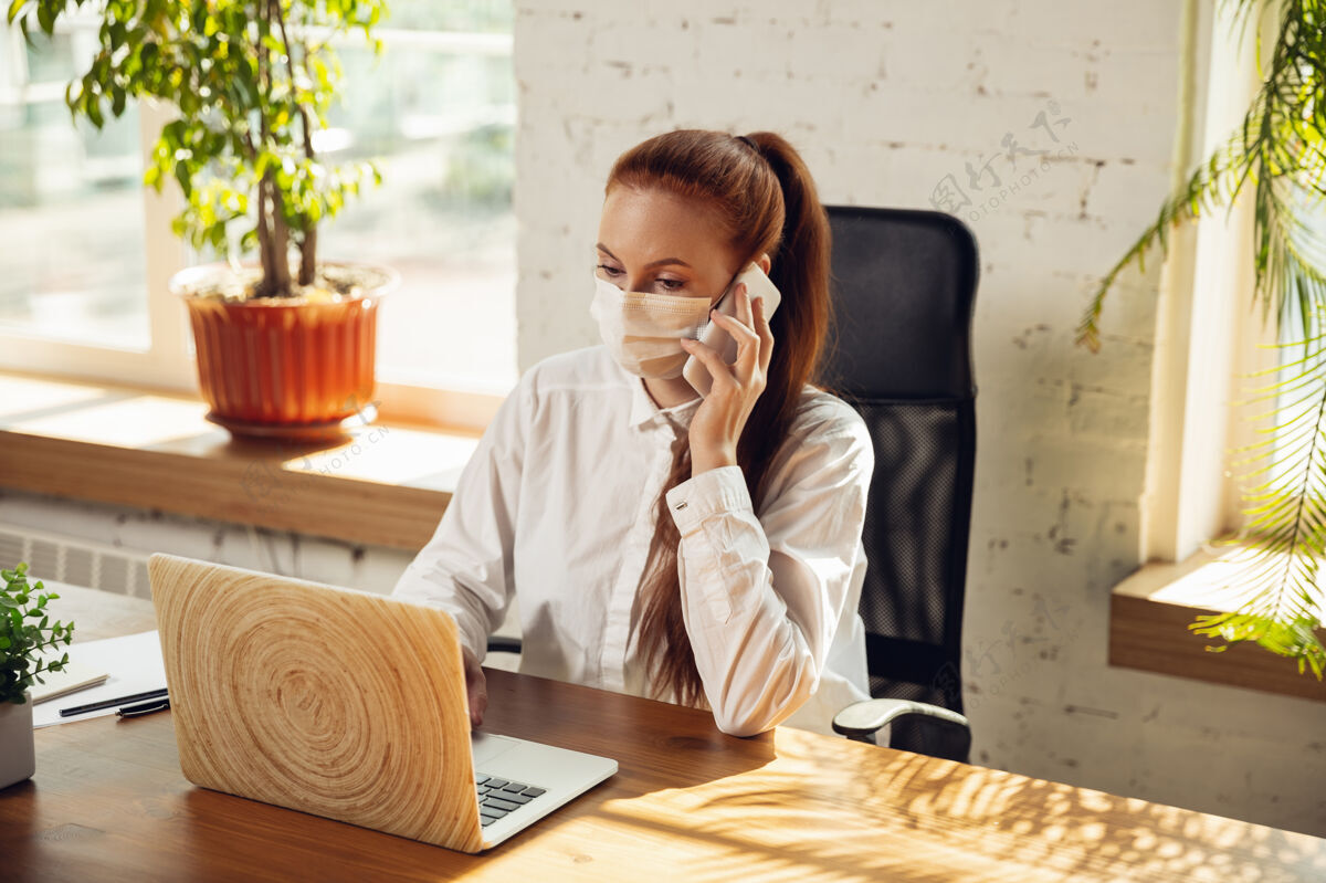 远程在冠状病毒或covid-19隔离期间独自在办公室工作的妇女 戴着口罩分析疾病女性