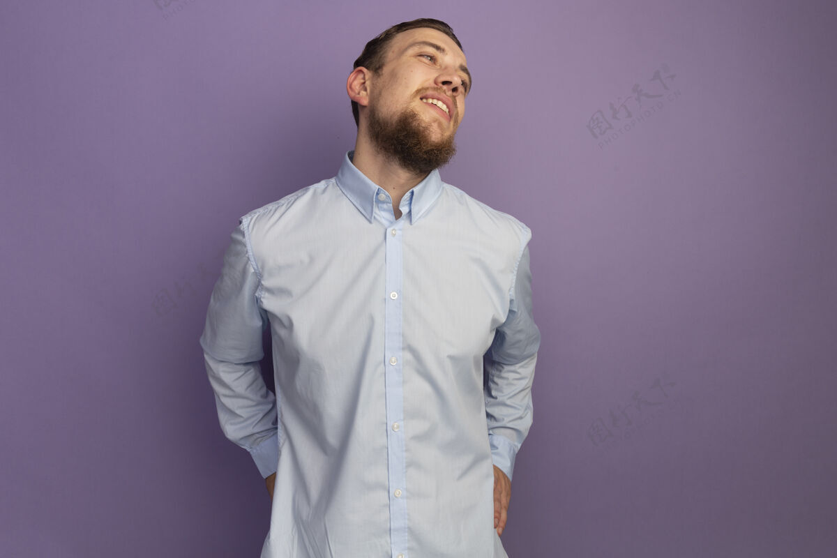 人高兴的金发帅哥看着紫色墙上孤立的一面侧线衣服男人