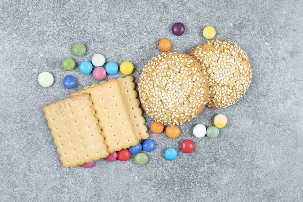 小吃饼干和五颜六色的糖果放在大理石表面美味芝麻餐
