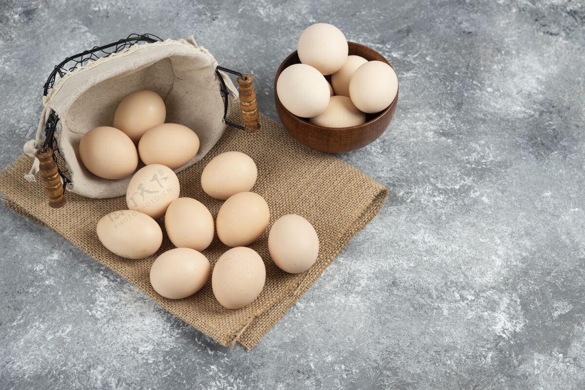 烹饪一篮一碗的有机新鲜生鸡蛋放在大理石表面上有机鸡衣服