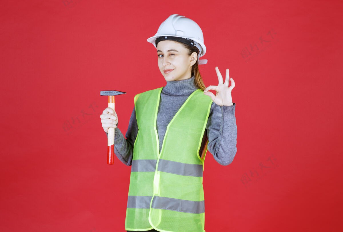 满意女工程师 头戴白盔 手持木斧 手举乐章晋升安全服装