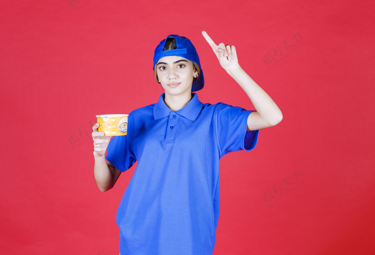 成人穿着蓝色制服的女快递员手里拿着一个黄色的面杯 有个好主意思维休闲方法