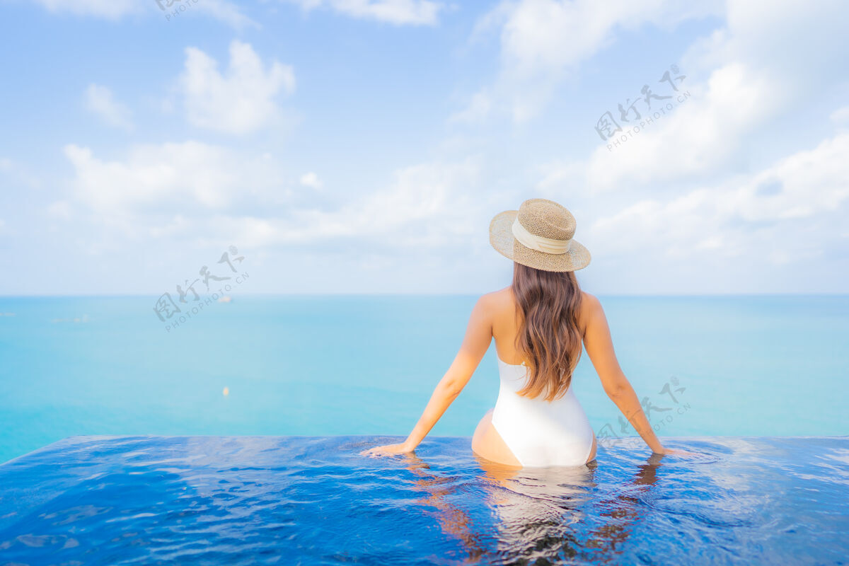 海滩肖像美丽的亚洲年轻女子放松微笑休闲在户外游泳池周围与大海在旅游度假泳装女性休息