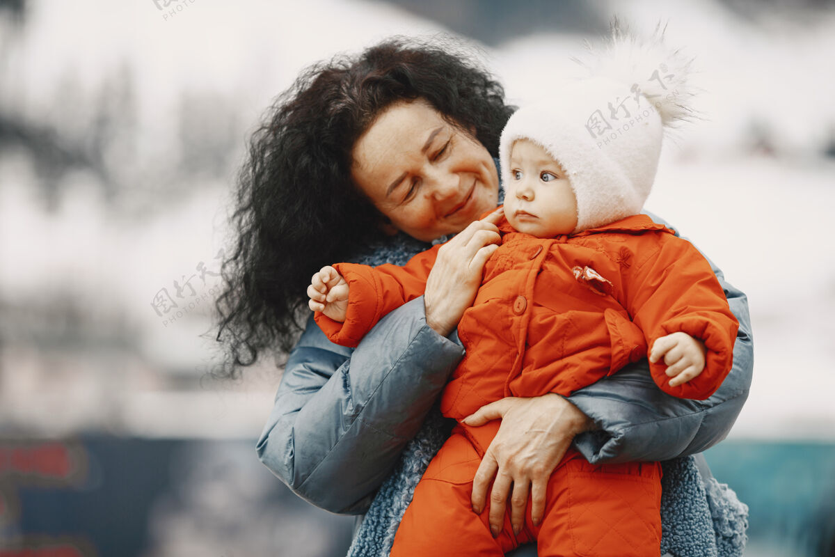 在一起穿着暖和衣服的婴儿奶奶和孙女站在一起冬天在山上度假寒冷公园女孩