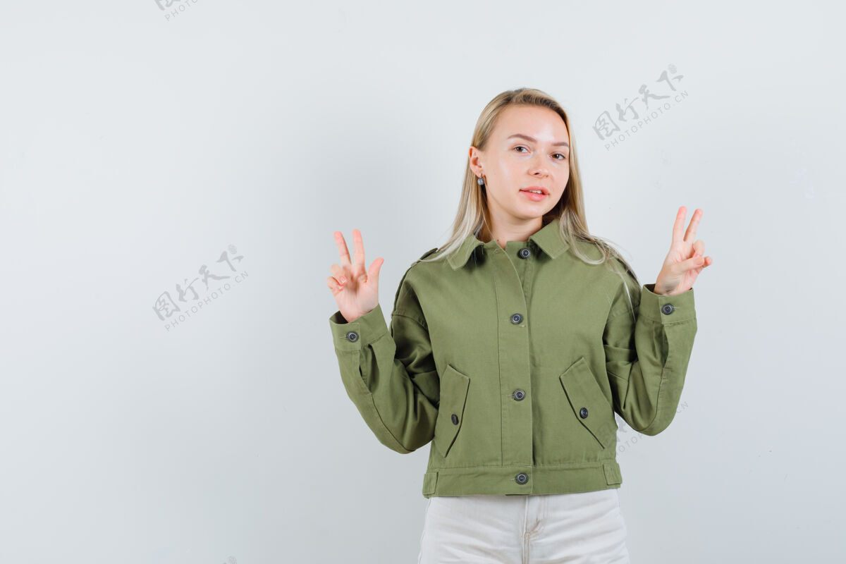 秀年轻女性穿着绿色夹克展示v形标志 看起来很快乐 正面视图快乐女孩年轻