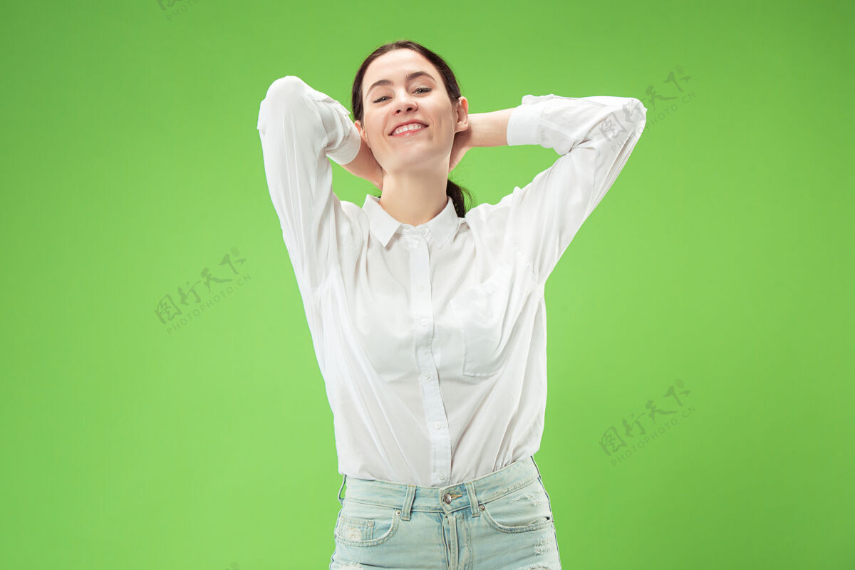 欢呼快乐的商业女性站在绿色的工作室背景上 微笑着美丽的女性半身像年轻的情感女性人类的情感 面部表情的概念人类成功表情