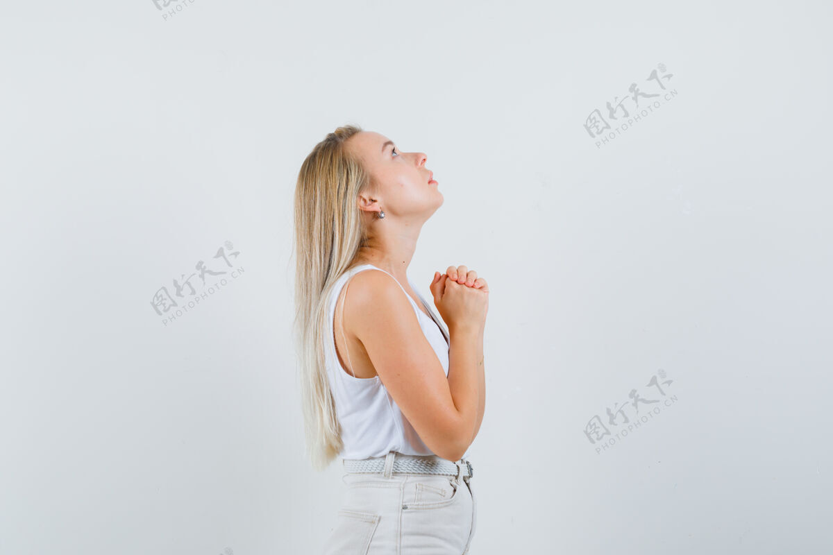 人一位金发碧眼的女士穿着紧身衣 裤子 双手合十祈祷 看上去充满希望手女性头发
