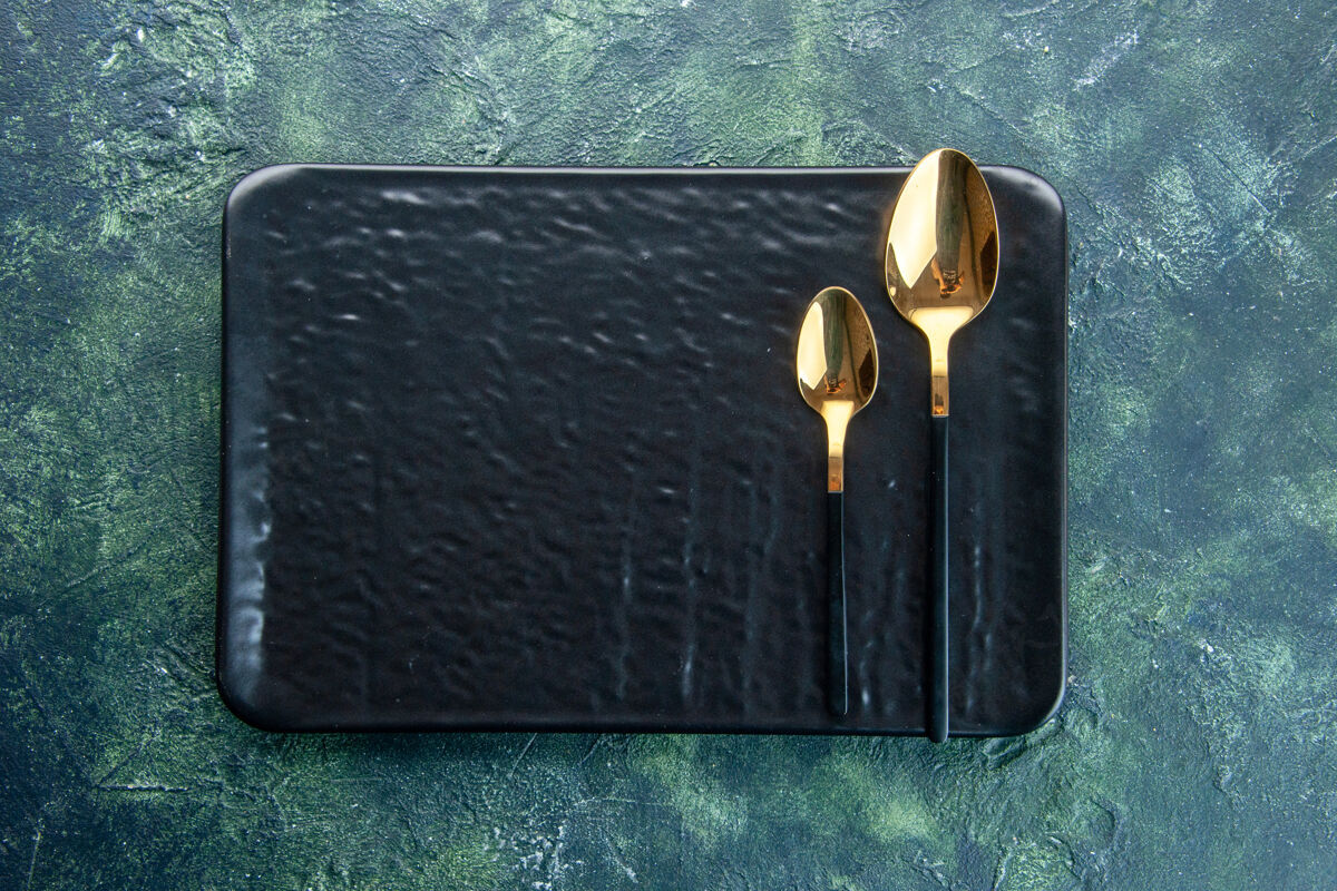 皮革顶视图黑色盘子和深蓝色背景上的金色勺子餐具颜色晚餐餐厅服务餐具上衣颜色包