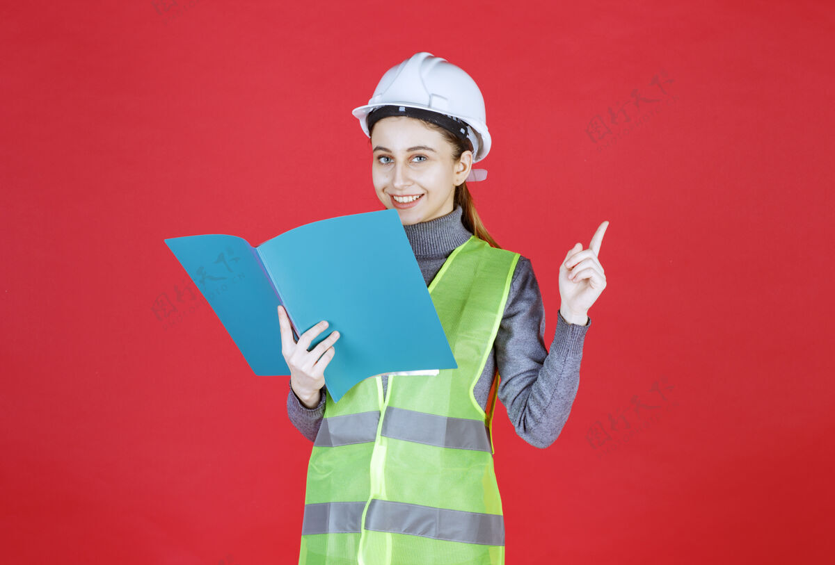 模特戴着白色头盔的女工程师手里拿着一份蓝色的工程文件 一边读一边想意见控制服装