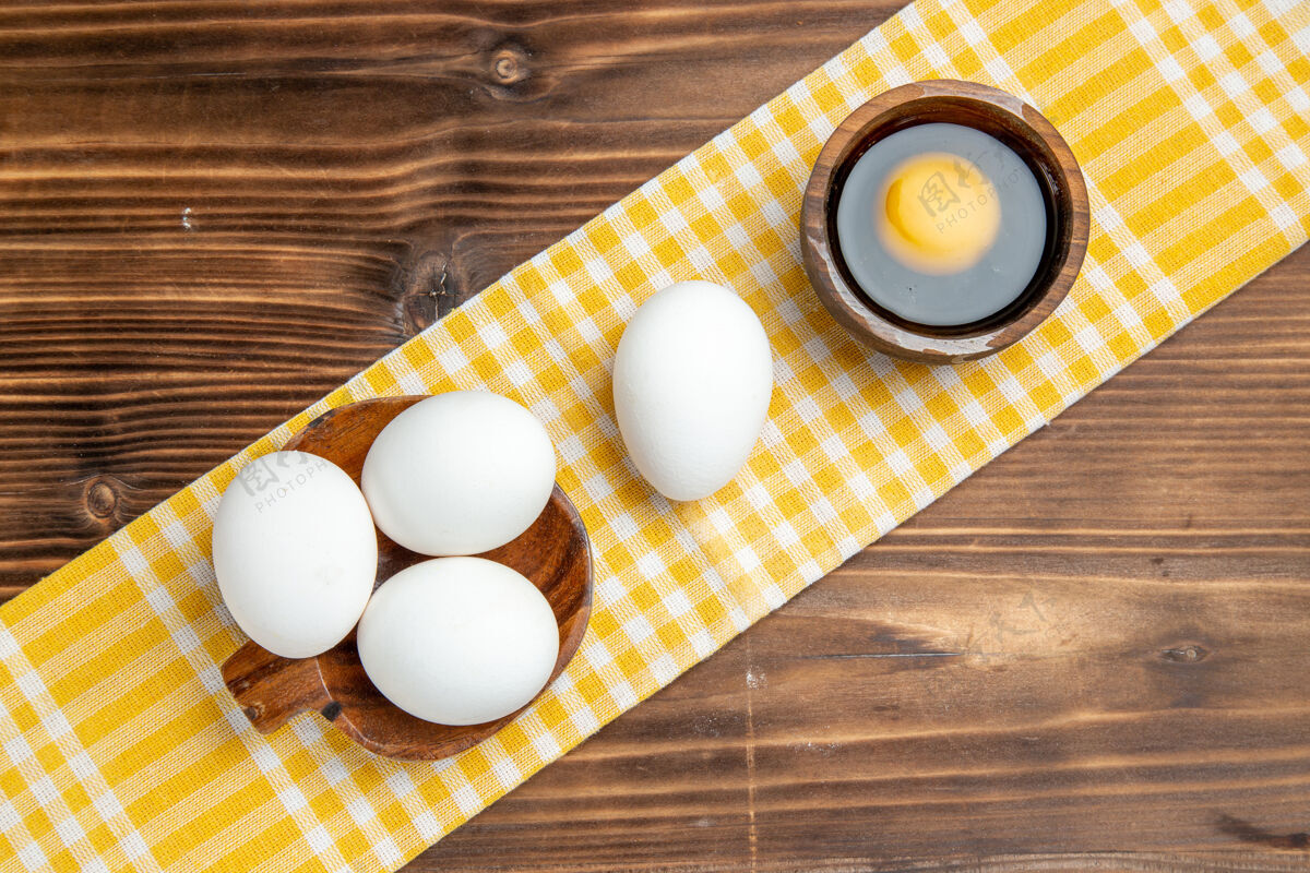 圆的俯视整个生鸡蛋放在棕色的木制餐桌上早餐吃木制鸡蛋鸡蛋风景早餐