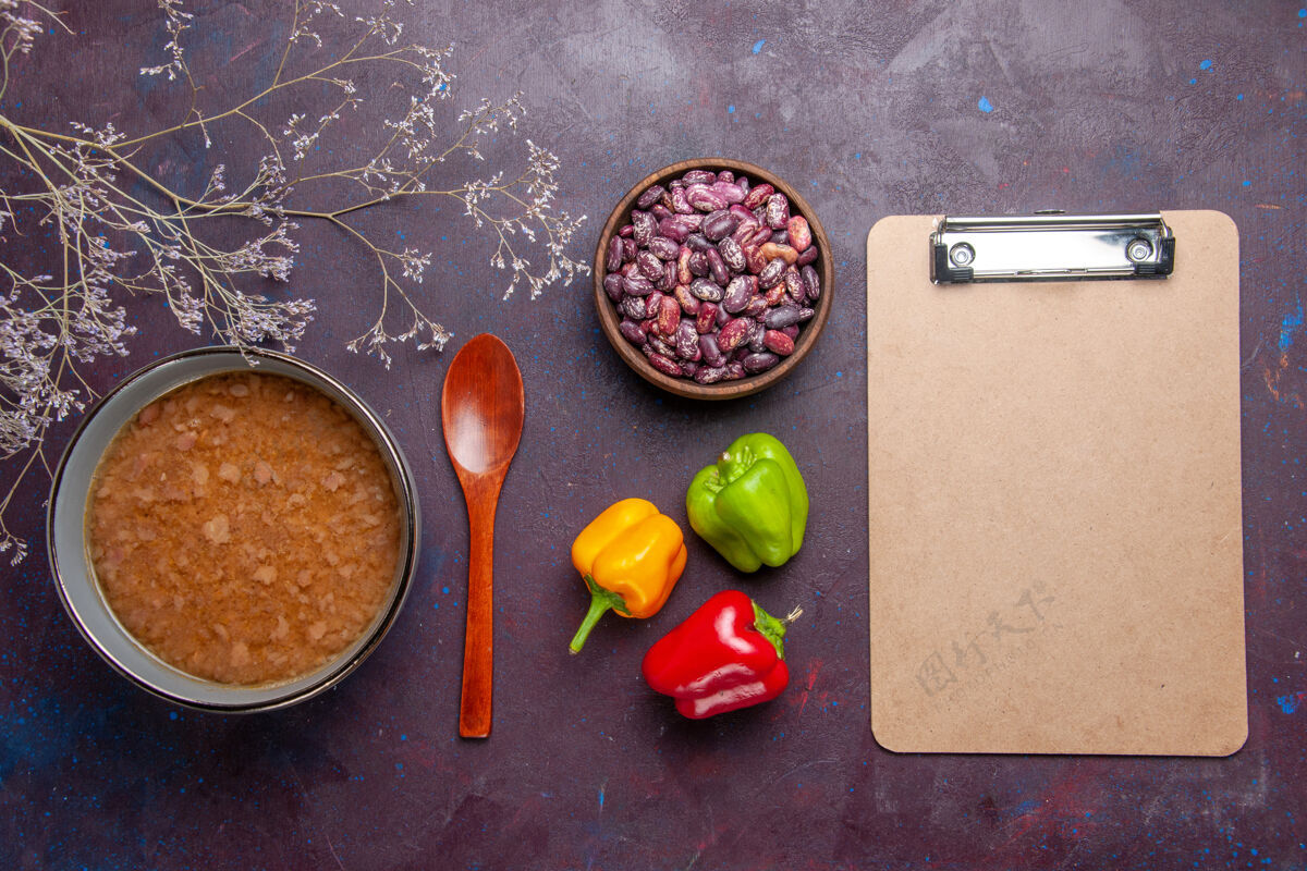 生的顶视图褐色的汤在盘子里用豆子放在深色的桌子上汤蔬菜餐食品厨房用油观点胡椒粉烹饪