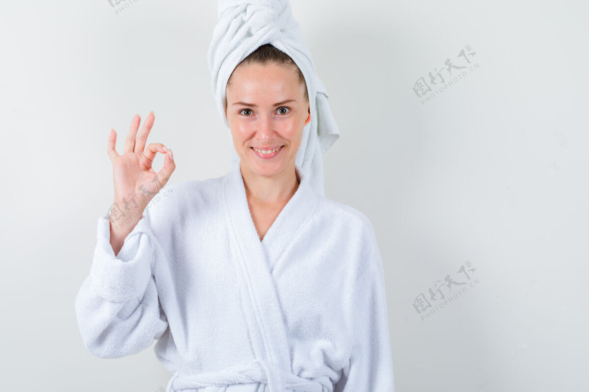 完美年轻的女士在白色浴袍 毛巾和显示良好的姿态 看起来很高兴 前视图皮肤水疗干净