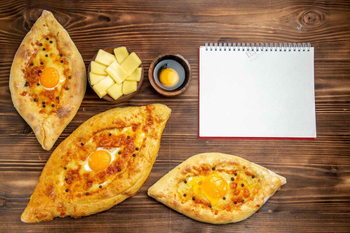 营养品顶视图烤鸡蛋面包从棕色木制书桌上的烤箱新鲜出炉面团鸡蛋面包包早餐烘焙生的桌子