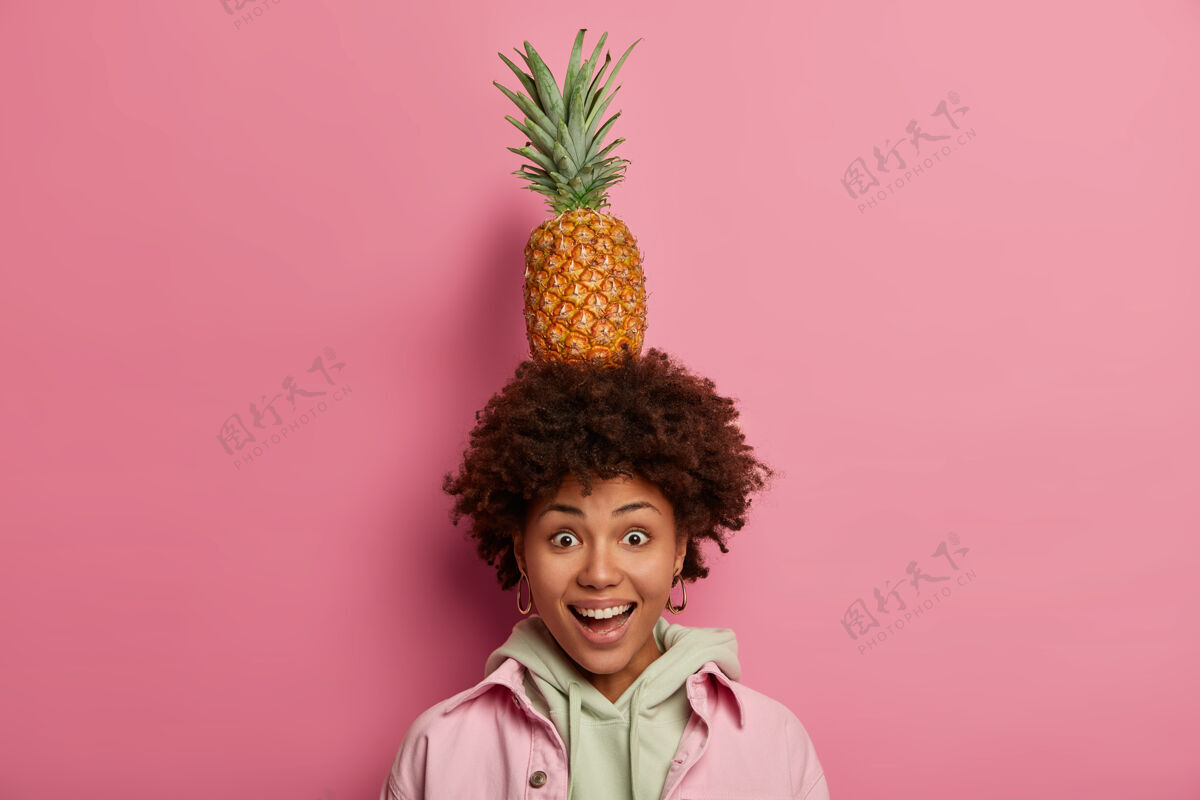 菠萝快乐的美国黑人妇女头上抱着美味的新鲜成熟的菠萝 高兴地看着镜头 独自享受热带水果的乐趣 心情愉快非洲营养美味