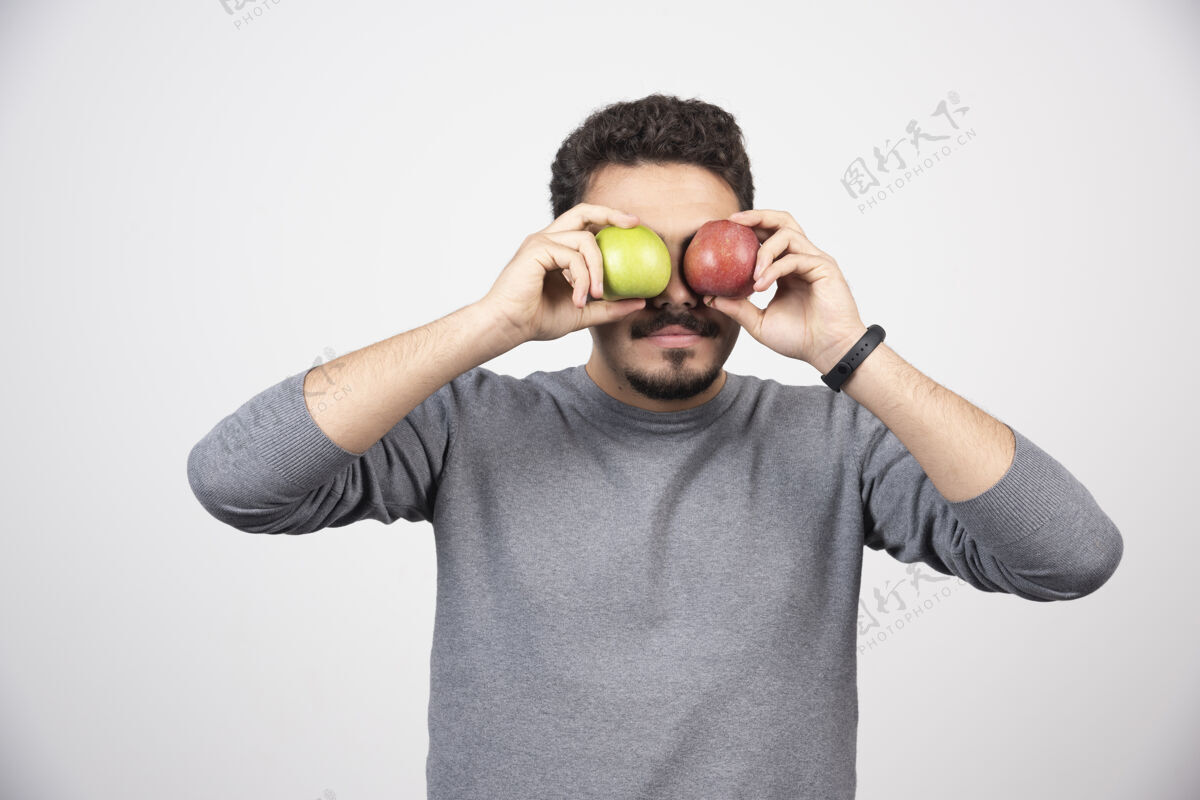 新鲜年轻的黑发男人用苹果遮住眼睛人类自然男孩