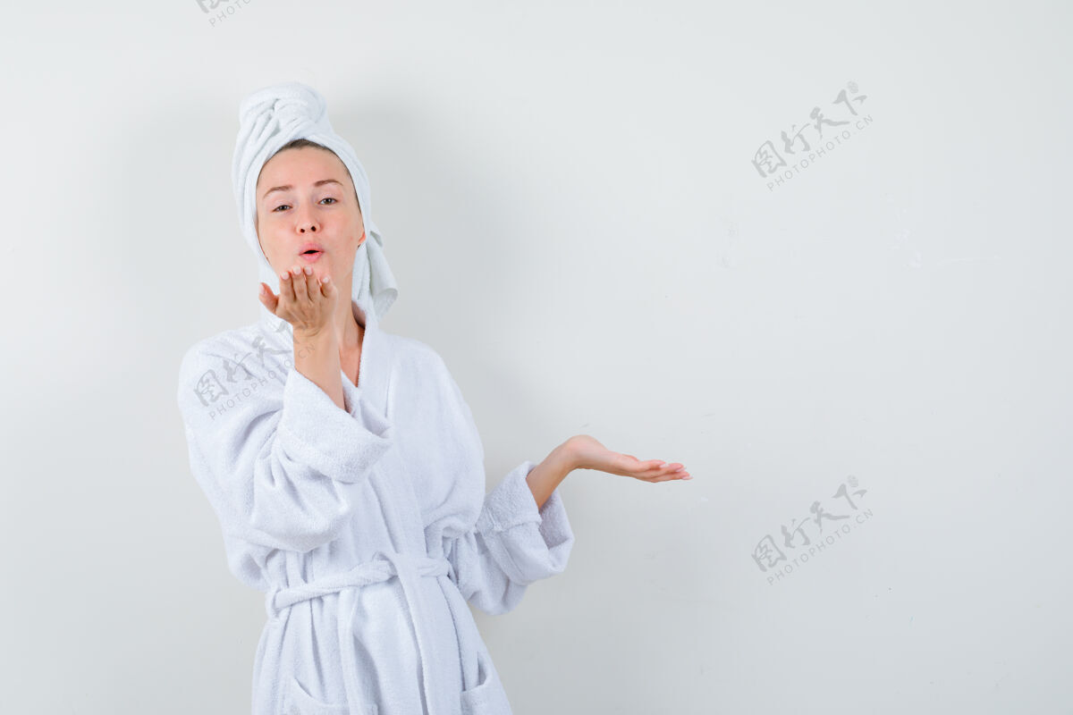 年轻年轻女子撅着嘴吹着飞吻 手伸开 穿着白色浴衣 毛巾 看起来很可爱正视图头发毛巾空气