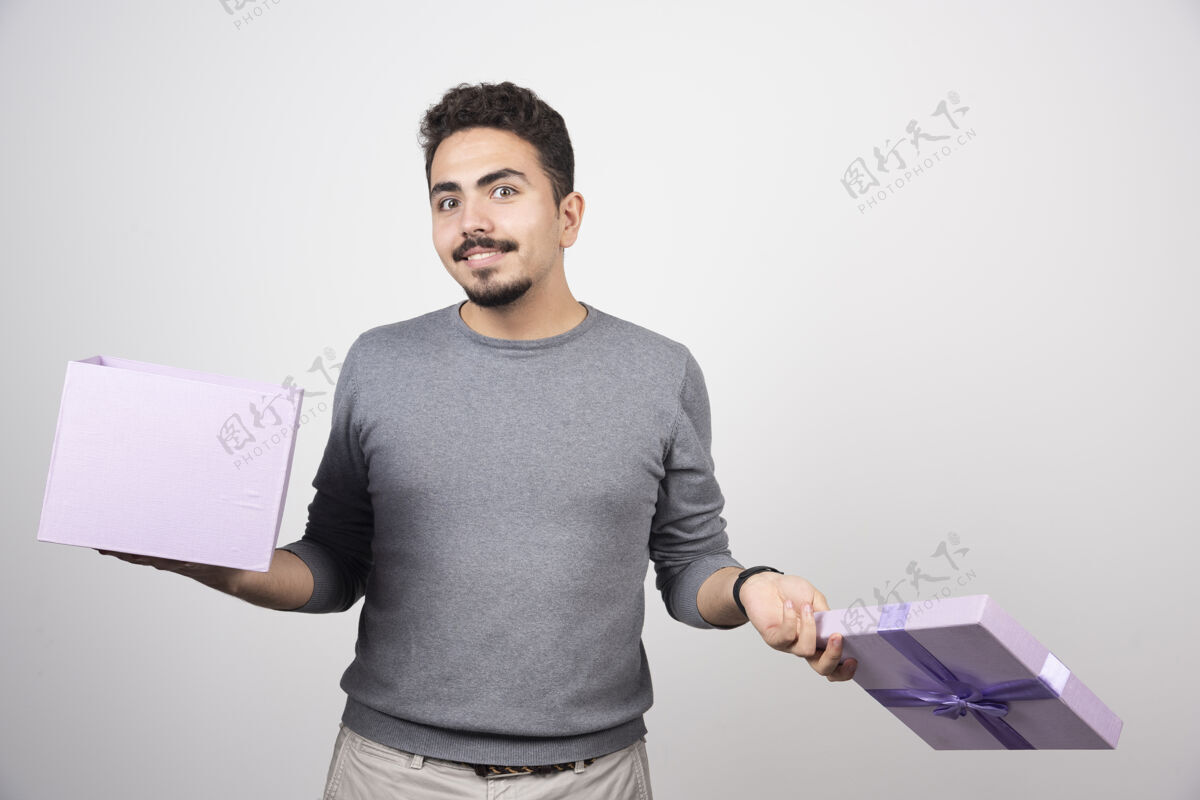 盒子带着微笑的男人 在白色的墙上放着一个打开的紫色盒子男人礼物礼物