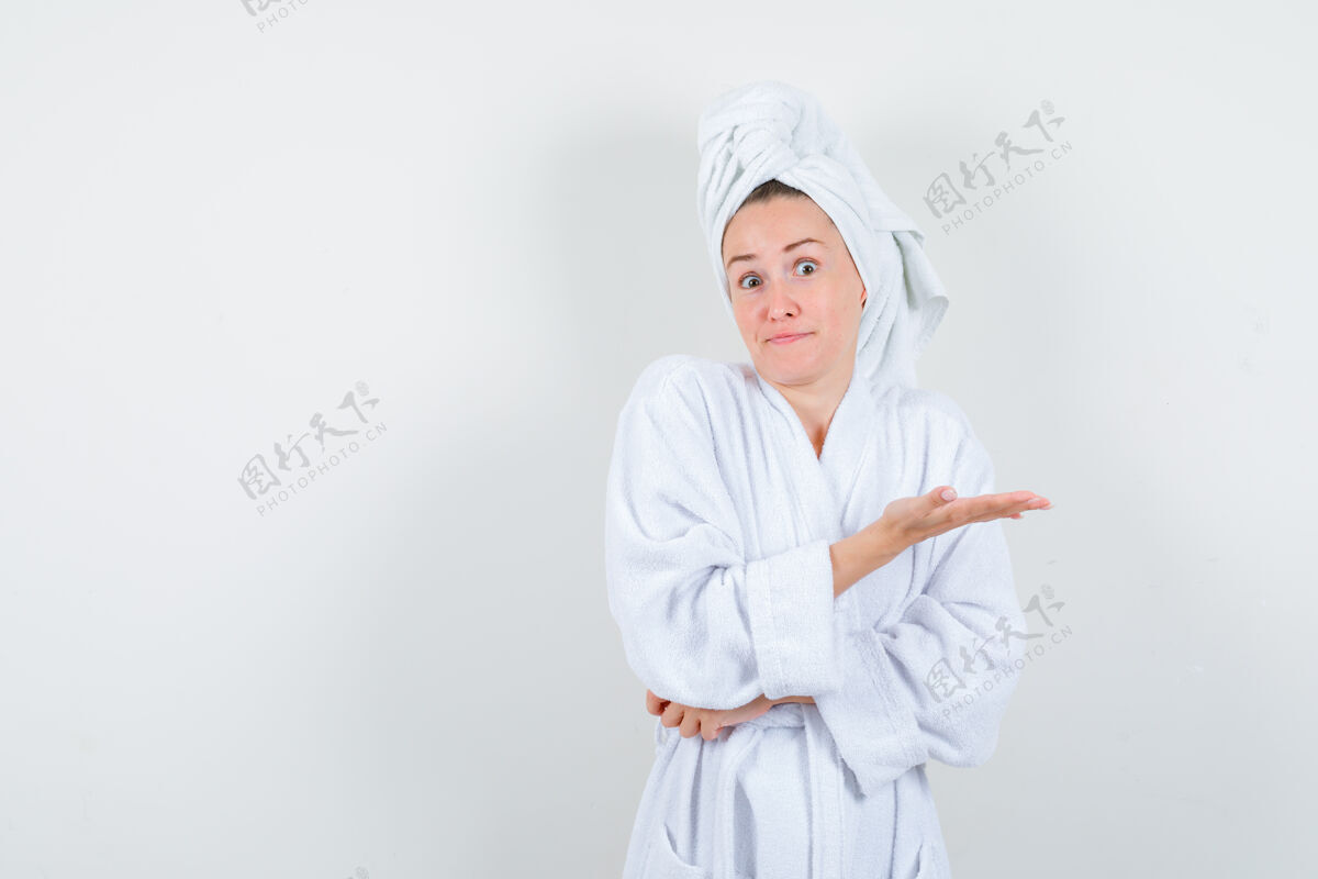 人年轻女子穿着白色浴衣 手心铺着毛巾 露出疑惑的神色 前视手掌微笑东西