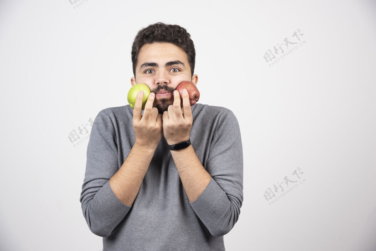 模特年轻的黑发男子拿着苹果紧挨着他的脸苹果年轻新鲜