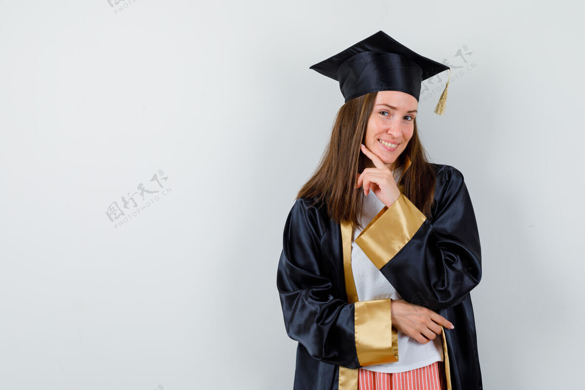 人民女毕业生穿着学院服 手指托着下巴 看上去很快乐 前视图大学前欢呼