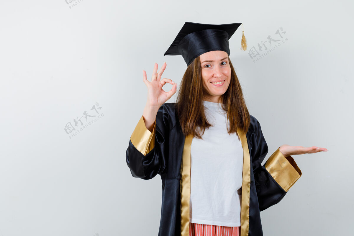 手势毕业女性的肖像 展示了ok的姿势 穿着休闲服 制服 面容欢快地摊开手掌正面手掌成人
