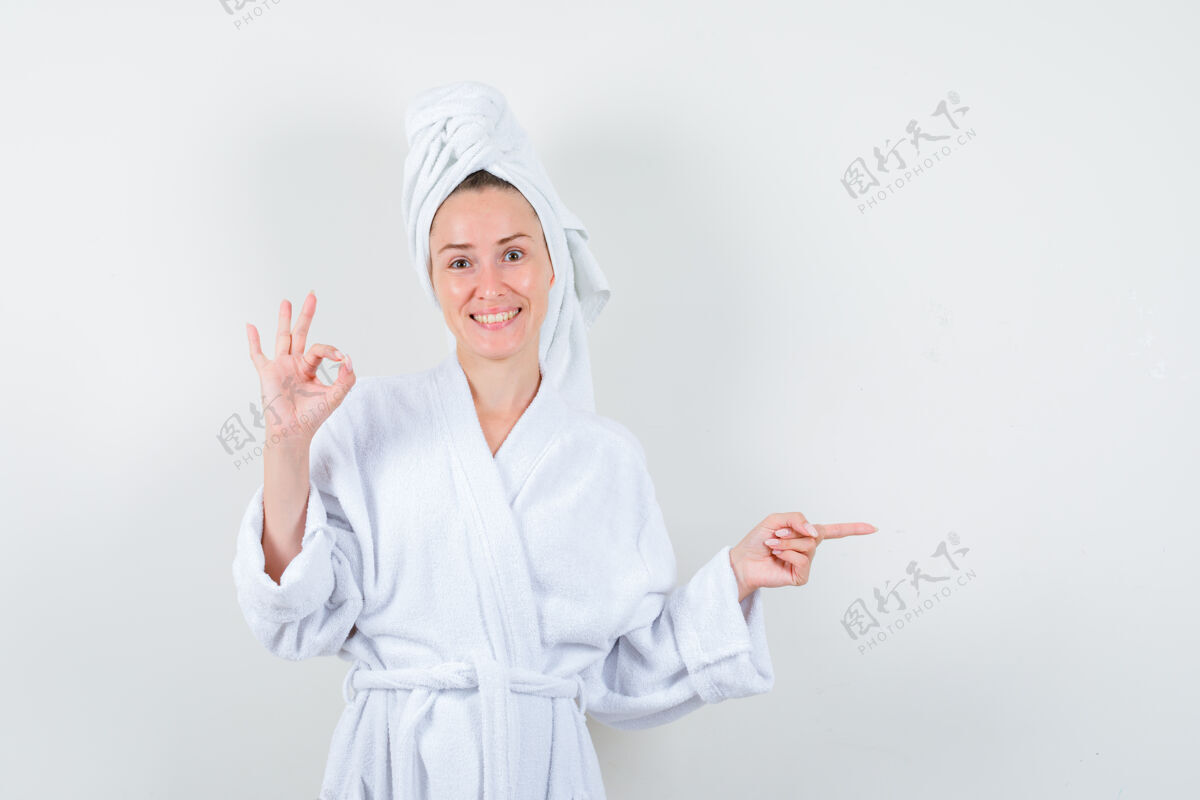 人年轻女子摆出ok的姿势 指着右边的白色浴衣 毛巾 神色开朗 俯视前方健康女性积极