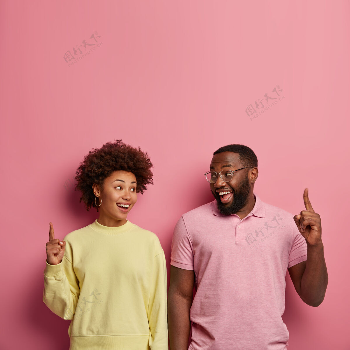 向上一对幸福的深色皮肤夫妇的垂直镜头指向前指上方的空白区域T恤垂直点